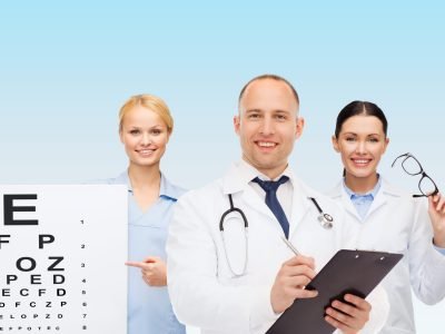 medicine, profession, teamwork and healthcare concept - international group of smiling medics or doctors with eye chart, clipboard and stethoscopes over blue background